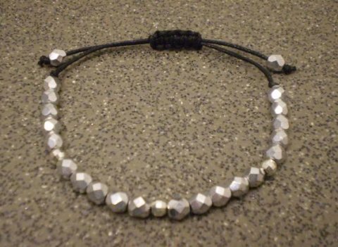 knyttet armbnd i vokset sort bomuldsnre med forslvede facetperler.