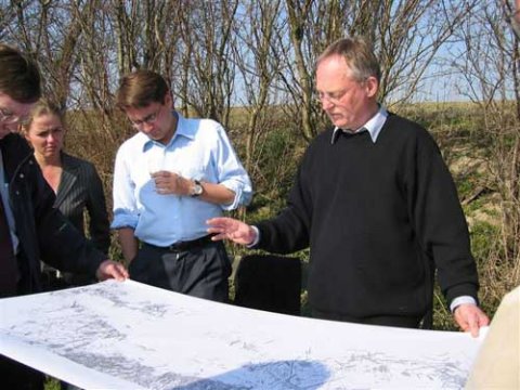 Brian Mikkelsen f&aring;r en indf&oslash;ring i, hvad udgravningerne i 1990erne har frembragt af oldsager fortalt af Nydamselskabets formand, Vincent Jessen. Folketingsmedlem i S&oslash;nderborgkredsen Ellen Trane N&oslash;rby (V) ser interesseret med. Medarrang&oslash;r af bes&oslash;get, Formand for De Konservative i S&oslash;nderborg, John Lohff, skimtes.